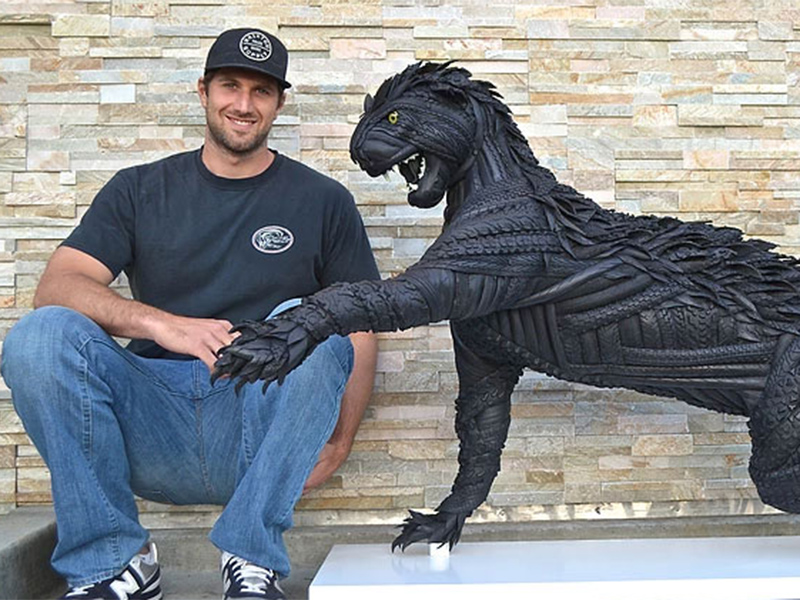 O atleta e artista Blake McFarland ao lado de uma de suas esculturas de pneu.