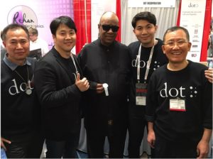 Stevie Wonder (centro) posa com o co-fundador da Dot,  Kim Ju Yoon (segundo da esquerda) e outros funcionários da empresa no estande de Dot na Conferência CSUN 2016.