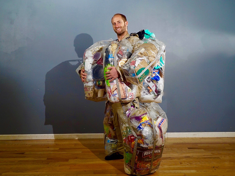 Rob Greenfield posa com sua roupa carregadora de lixo.