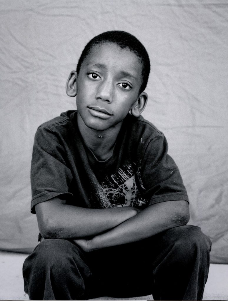 Foto garoto negro refugiado com um sorriso leve