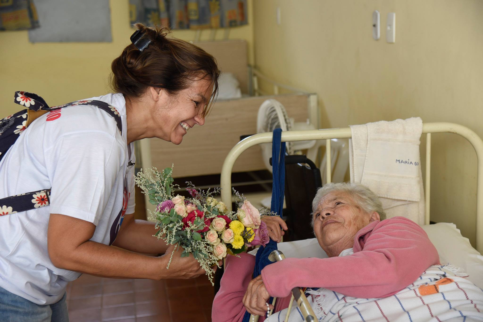 Voluntária do grupo Flor Generosa entrega buquê de flores a idosa. Foto Divulgação